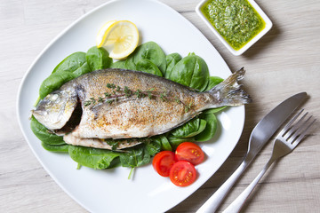 Baked Dorado with spinach and pesto sauce. Close-up. Selective focus.