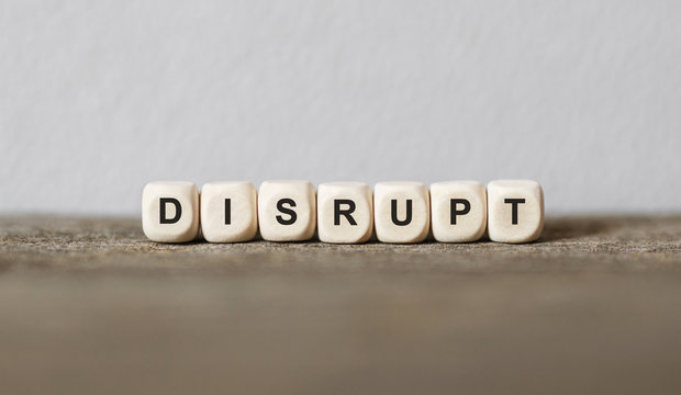 Word DISRUPT made with wood building blocks