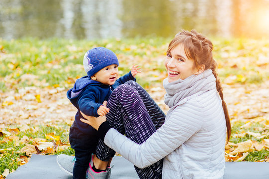 Series photo of sporty mother with infant baby boy workout together in autumn parl. Infant boy with mother sitting on yoga mat in autumn park. Multitasking, healthy life and recreation concept