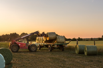Obraz premium Ein Traktor lädt Ballen vom Anhänger aufs Feld um