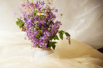 Bouquet of bloomin lilac in vase on fabric background.