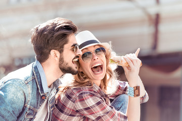 Couple eating sandwich and talking outdoor.