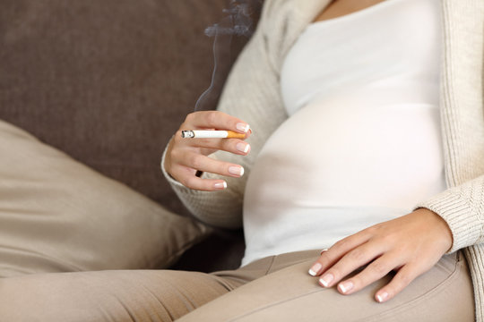 Irresponsible pregnant woman smoking a cigar