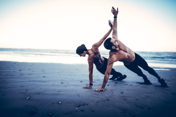 Young adult couple doing fitness exercises on beach