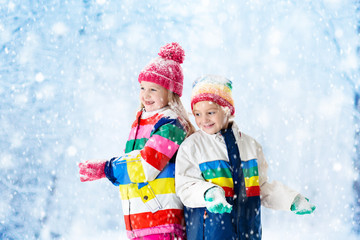 Kids playing in snow. Children play outdoors in winter snowfall.