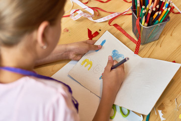 High angle portrait of teenage girl  making gift card for mom on Mothers day during art and craft class in school
