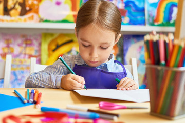 Portrait of adorable little girl  drawing pictures during art and craft class in pre-school