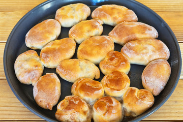 Freshly baked homemade pies and buns on a round dish for baking