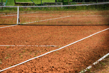 Tennis net at empty red gravel court 