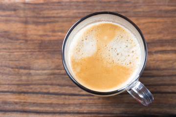 Glass of americano espresso fresh made dark black strong coffee on wooden board table, thick froth foam in cafe, morning refreshing hot drink caffeine, copy space for text