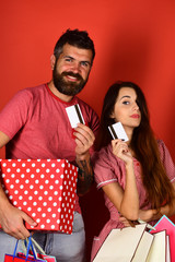 Couple in love holds shopping bags on red background