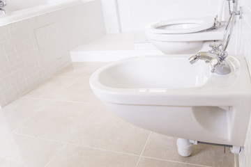Fototapeta na wymiar white bidet next to the toilet in the bathroom of the apartment or hotel room. modern interior