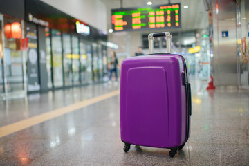 Suitcase on wheels standing on the floor in modern airport terminal. Copy space