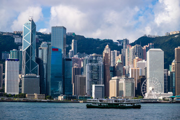 Fototapeta premium Hong Kong skyline and skyscraper cityscape, passenger ferry boat traffic on Victoria Harbor at morning dawn