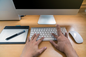 Top view of closeup hand with weir wrist to working with computer keyboard with mouse and technology computer desktop and hard disk enclosure on the wooden table, hardworking and overdo injury concept