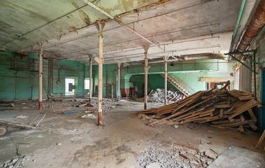 Fototapeta na wymiar Destroyed production room of an old abandoned textile factory with remains of broken equipment
