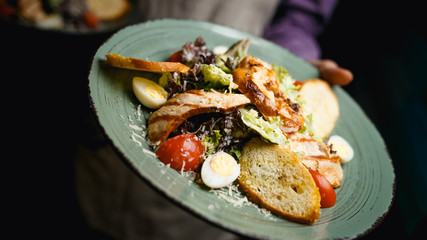 Caesar salad delicious dish Italian with chicken, eggs, tomatoes, lettuce and bread on vintage plate restaurant