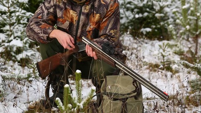 Hunter charges a hunting rifle with cartridges in winter forest
