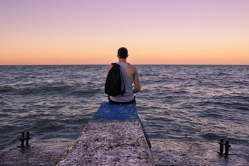 the man sits at sunset on the pier and looks far into the sea, the Crimea