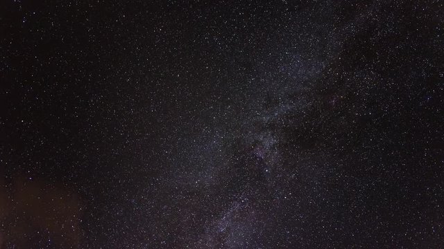motion time lapse of the Milky Way Galaxy in the region of the celestial Summer Triangle moving through the night sky full of stars with clouds appearing at the end