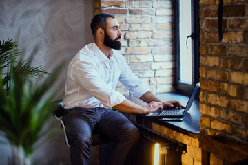 Stylish bearded male works with a laptop.