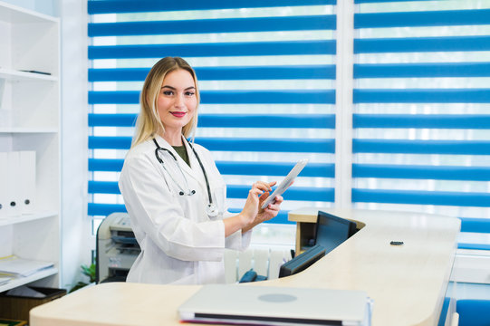 Young Female Receptionist Holding Tablet Computer In Hospital