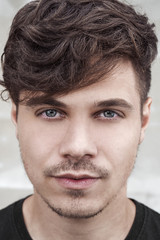 Obraz premium Illuminated portrait of handsome man on white background. Male model with curly long hair. Portrait of fashion model with long hairstyle and with green eyes 