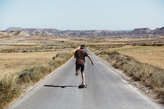 Man riding skateboard on prairie road