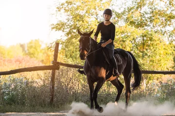 Foto op Canvas Young pretty girl riding a horse with backlit leaves behind © Dusan Kostic