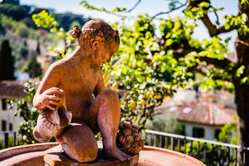 Small statue of girl with lemon tree backdrop.