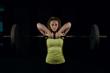 A young girl is lifting a barbell in the gym. Sport