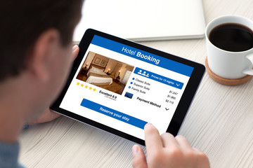 Man holding computer tablet with app hotel booking on screen