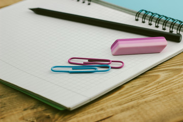 green notebook on a wooden table with pencils