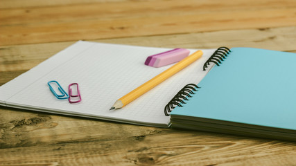 green notebook on a wooden table with pencils