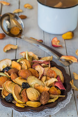  A mixture of dried fruits in an old brown vase and freshly prepared compote in a small saucepan on a wooden table. Delicious and healthy drink.