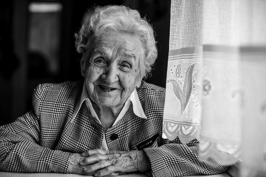 Black and white portrait of a smiling elderly woman.