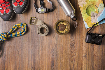 Overhead view of travel equipment for an adventure trip on wooden floor with copy space. Adventure travel concept.