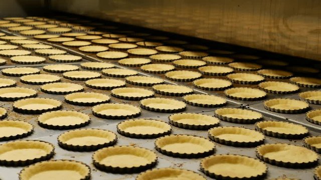 Industrial process of Empty Pies base pastries made from biscuits and butter on a conveyor belt in a bakery factory