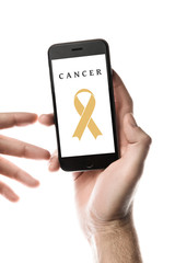 Hand holding smartphone, blank screen with gold ribbon isolated on white background. World Cancer Day. Childhood cancer concept
