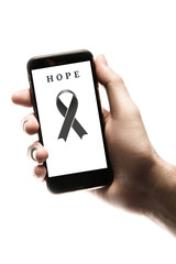Hand holding smartphone, blank screen with black ribbon isolated on white background. World Cancer Day. Melanoma concept