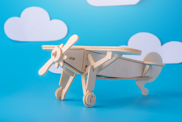 Wooden toy airplane on a background of blue sky with paper clouds. Concept travel and airlines
