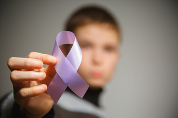 healthcare concept - child hands holding cancer awareness ribbon