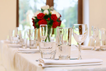 Beautifully set festive table, decorated with a bouquet of roses. The preparations for the party
