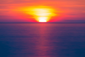Obraz na płótnie Canvas Long exposure view of the half of setting sun over the sea horizon