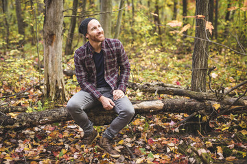 Confident and handsome. Handsome young man in the background and orange fallen leaves on the floor