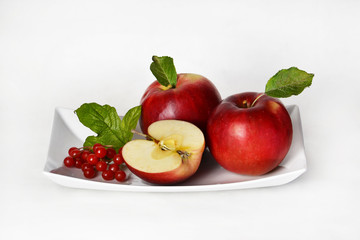 Ripe red apples on a white plate.