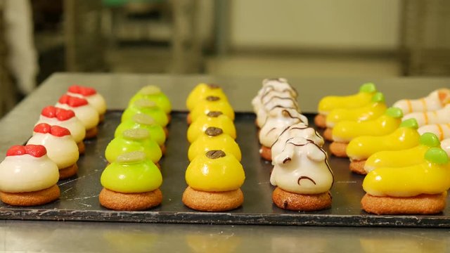 Petite fours pastry colorful sweet cakes presented on a black plate