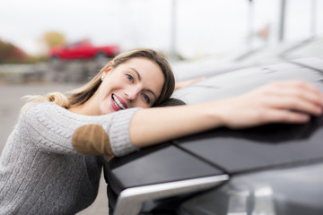 Obraz na płótnie Canvas Jolly young female driver hugging her new car