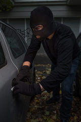 Masked man stealing a car