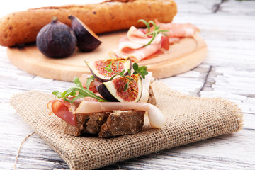 Sandwich with figs and prosciutto. Antipasti gourmet bruschetta snack.